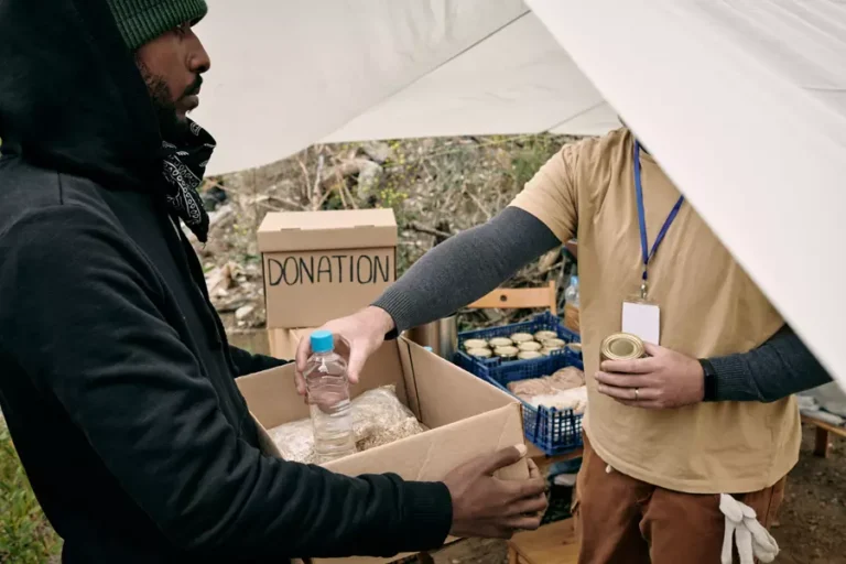 young-refugee-man-holding-box-while-volunteer-putt-2021-10-20-03-17-47-utc.webp
